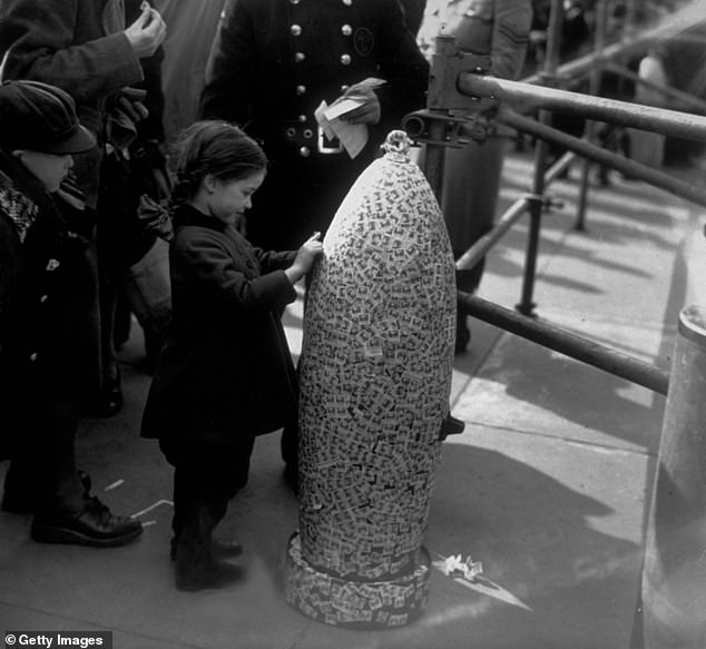 A little girl sticking 'Wings for Victory¿ stamps on to a 500lb bomb case in Trafalgar Square