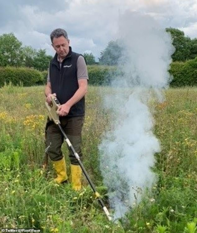 A gardener using a RootWave device to get rid of weeds in a field