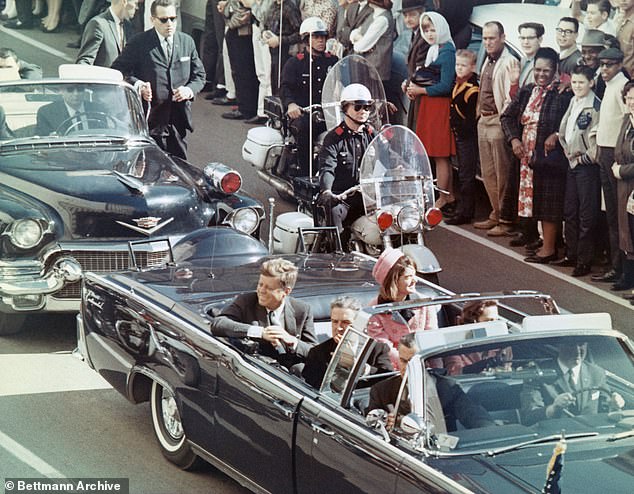 President John F. Kennedy and the first lady smile at the crowds lining their motorcade route in Dallas, Texas, on November 22, 1963. Minutes later, the president was assassinated.