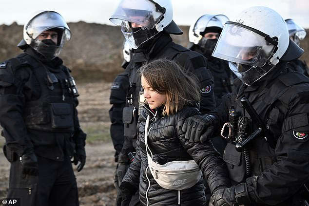 Police officers lead Swedish climate activist Greta Thunberg away from the edge of the Garzweiler II opencast brown coal mine today