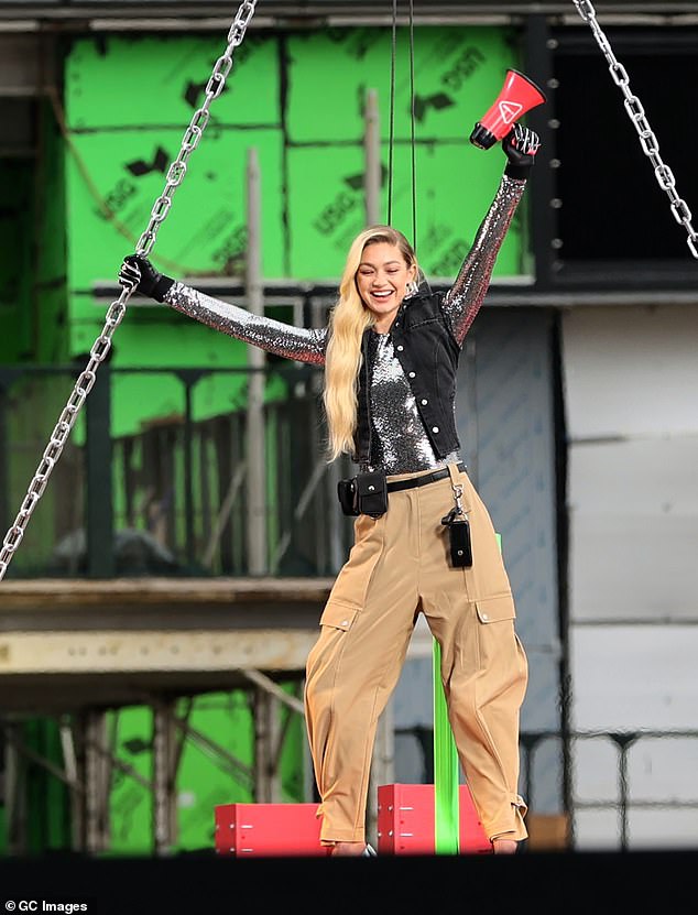 Safety first: The catwalk star appeared to have her own harness to keep her safe in the event of an accidental fall, and she held on to the thick metal chains that held up the beam for support.