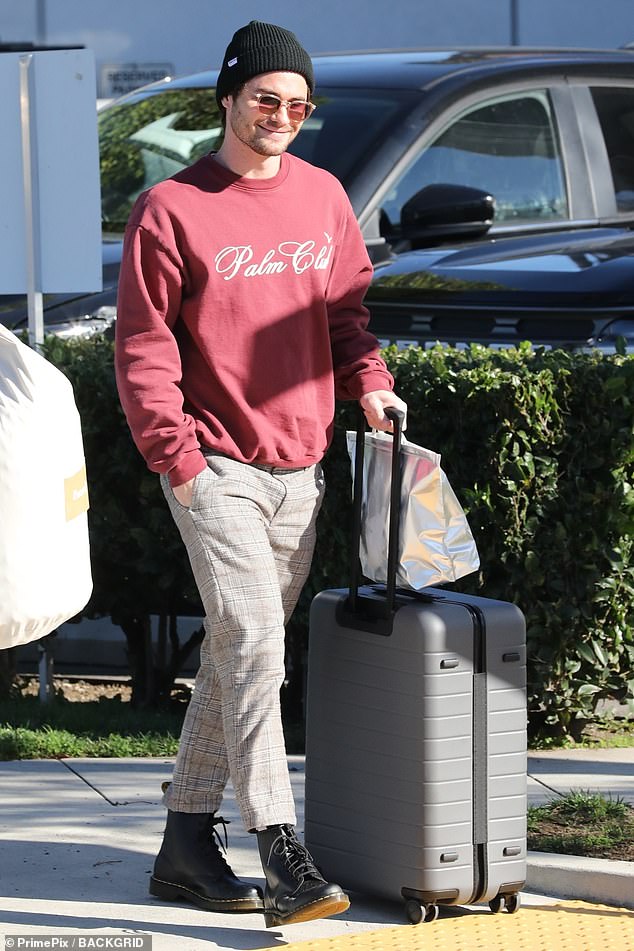 Bundle up: The Outer Banks actor, 30, donned a red 'Palm Club' sweatshirt with white pants covered in a checkered pattern