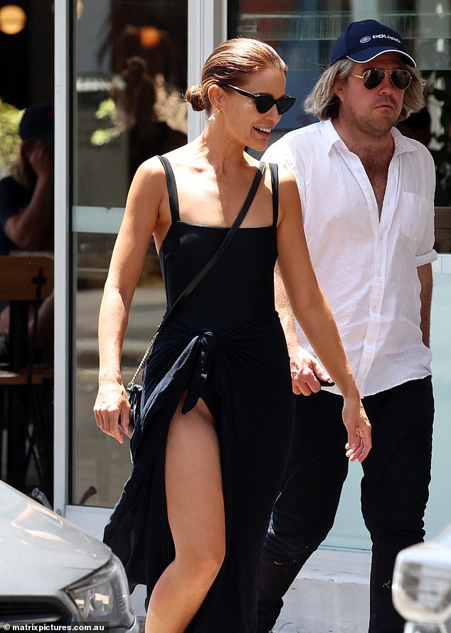 The 37-year-old former Home and Away star showed off her athletic figure in a high-cut black swimsuit while trying to cover her waist and legs in a black sarong that tied into a skirt.