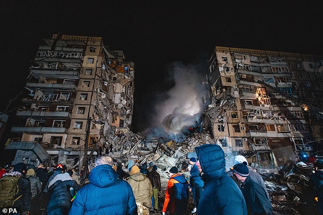 Pictured: Dnipro residents gather in front of a destroyed Ukrainian apartment building that was destroyed by a Russian missile on Saturday.