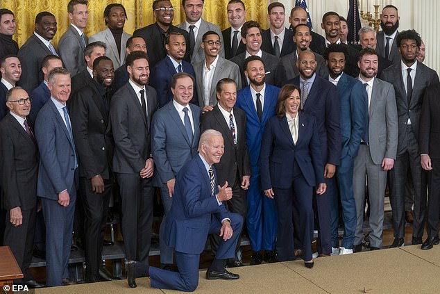 Biden is shown kneeling with a thumbs up as Kamala stands with one foot on the platform as they pose with the Golden State Warriors NBA team.