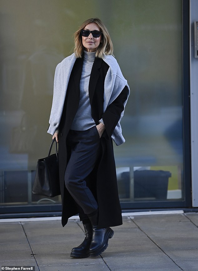 Winter chic: She stayed warm under a long black wool coat and tossed a coordinating sweatshirt over her shoulders while hiding behind a pair of dark sunglasses.