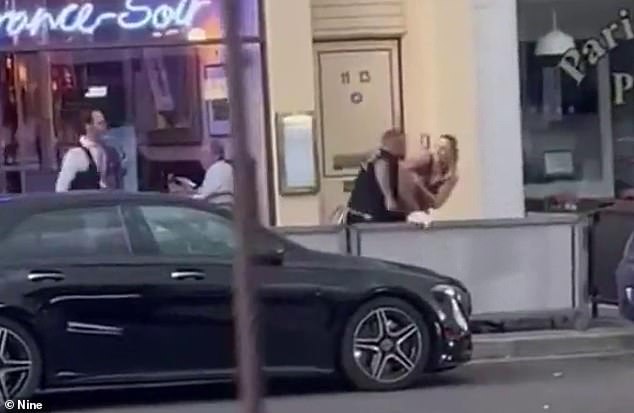 The footage shows a woman trading blows with a man, while several others also trade blows.