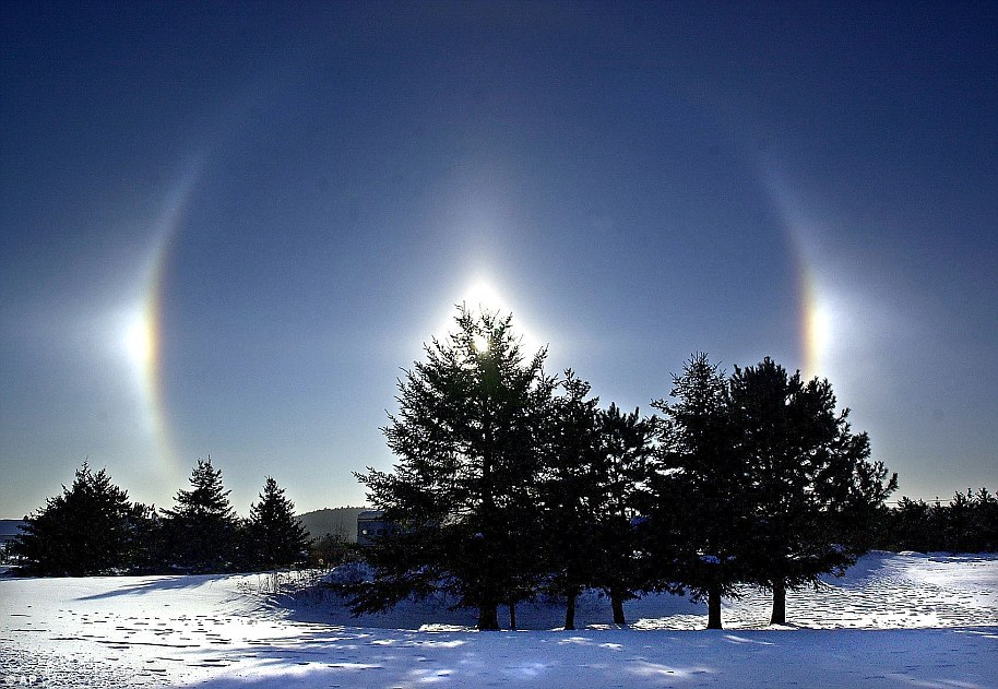 Sundogs or parhelia are seen over a snow-covered field in Duluth.  Sunrises, also known as phantom suns due to the bright spots on either side of the sun, appear when sunlight near the horizon is refracted by ice crystals in the atmosphere