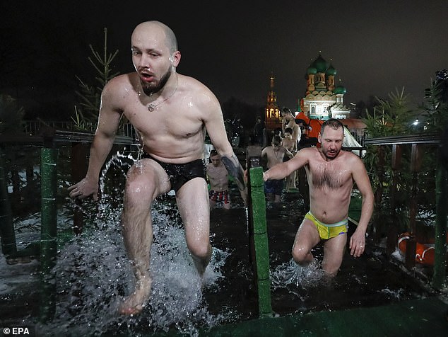 Two Russian men take a dip in the icy water of a pond during celebrations for the Orthodox Epiphany holiday, in Moscow, Russia, on January 18, 2023.