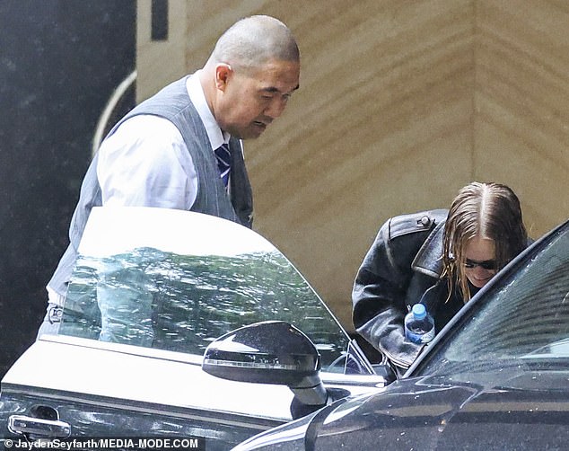 She kept her head down, but could be seen briefly smiling as she got into the car as a hotel staff member opened the door for her.