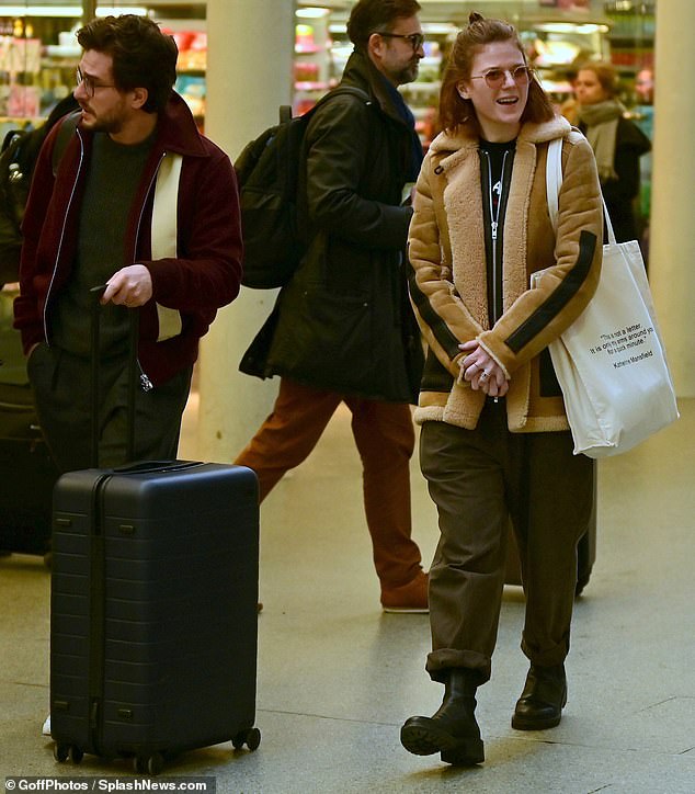 Journey: Kit looked to the side as his wife carried a white bag with all her essentials through the station.