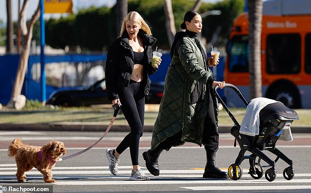 Multitasking: She wore a forest green puffer coat and a Bottega Veneta bag on her arm as she walked, pushing the stroller with one hand and carrying a cup of iced coffee in the other.