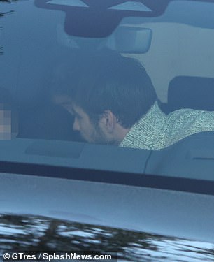 Doting dad: as he leaned close to his son in the back while appearing to fasten the young man's seatbelt, as they drank canned juice in the car