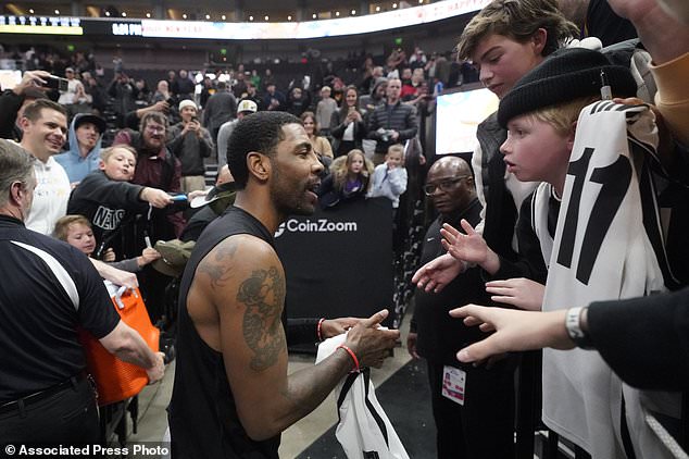 Brooklyn Nets guard Kyrie Irving, center, speaks to a fan after their victory over the Utah Jazz after an NBA basketball game Friday, Jan. 20, 2023, in Salt Lake City.  (AP Photo/Rick Bowmer)