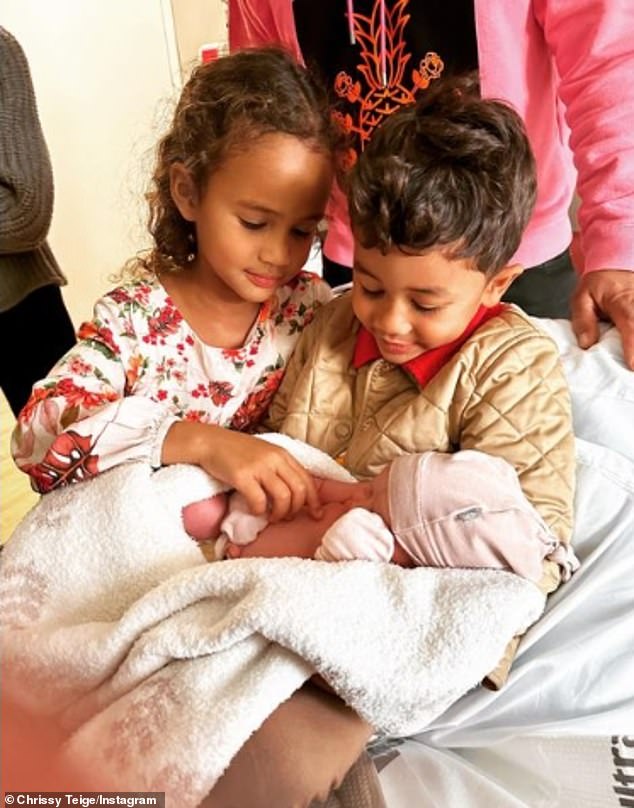 Baby glee: Teigen and the legend recently posted a sweet photo of their new baby being cuddled by her older siblings: six-year-old sister Luna and four-year-old brother Miles