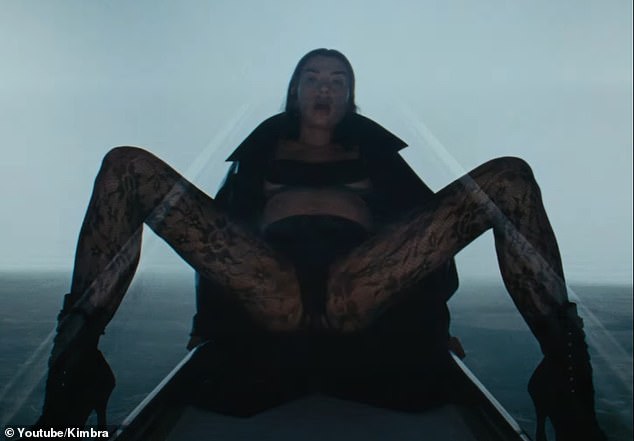 At one point, she spreads her legs wide so the camera shows a close-up of her crotch.