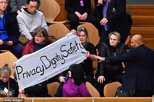 Protesters display a banner in the public gallery of the Scottish Parliament.