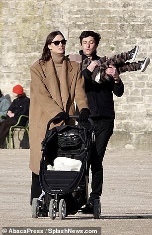 In his arms: Shielding her eyes with a pair of black sunglasses, Karlie pushed her son's empty stroller while the little one was in his father's arms.