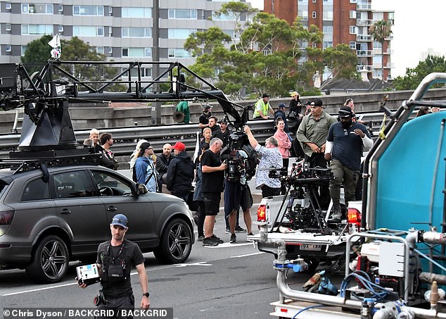 Photos from the bridge showed production in full swing in the port city with Gosling squatting next to his stunt double.