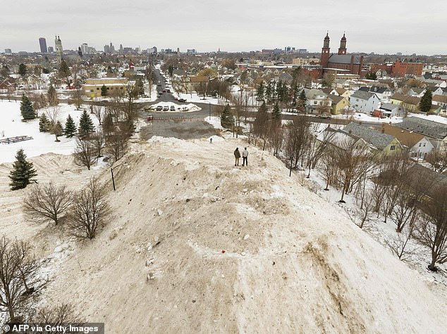 Residents enjoy the view from the top of a giant pile of snow in front of the Central Terminal in Buffalo, New York on December 29, 2022.