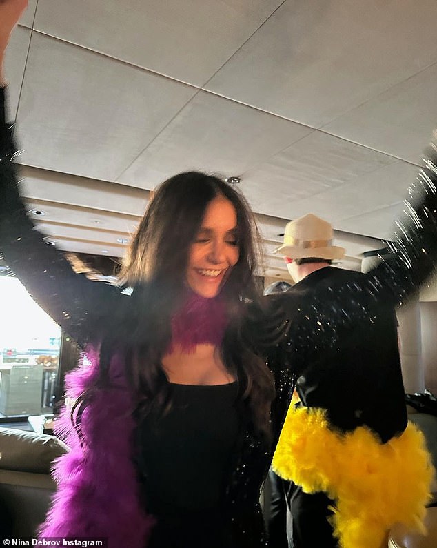 Party time: The actress could be seen wearing a purple feathered scarf around her neck with another guest in a yellow scarf trailing behind her as she danced in the small space