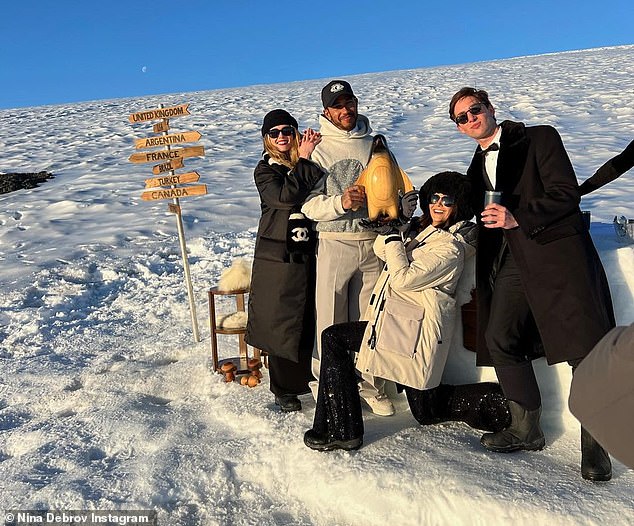 Having fun: The star-studded group later emerged from the boat to catch a memorable snap with a little wooden penguin next to what appeared to be a snow-covered makeshift table.