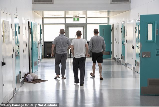 Three inmates exercise by walking down the corridor of the Alexander Maconochie Center