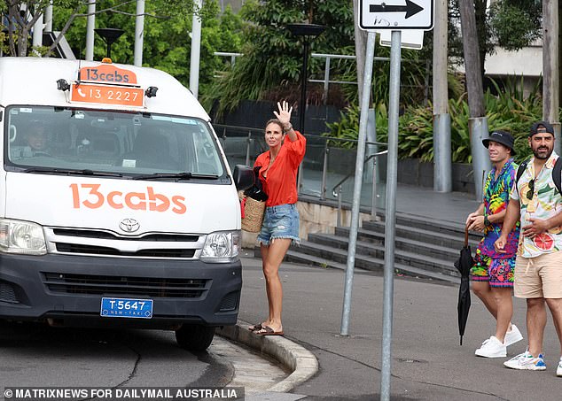 Candice waved while holding a large bag before getting into a waiting taxi.