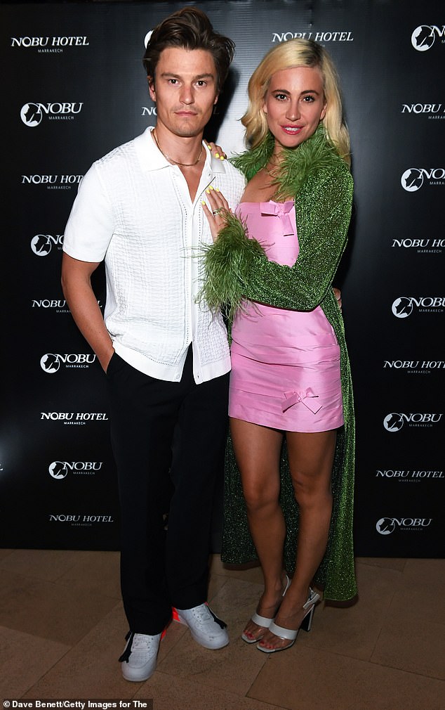 Glam: Pixie, donning another fabulous outfit, looked sensational as she graced the cameras in a pink satin mini dress  The blonde beauty also accessorized the sparkly ensemble with a green glitter-trimmed cardigan that featured a feathered collar and cuffs for dramatic effect.