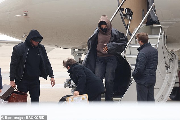 Casual: The 25-year-old cosmetics mogul dressed in a brown hoodie and sleek black trench coat as she stepped off her plane.