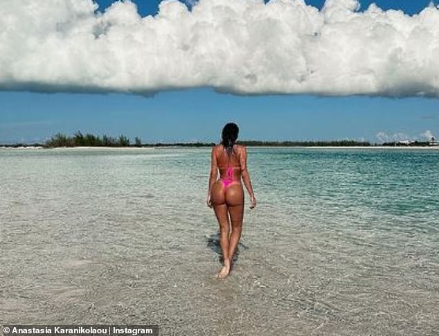 Tanned: The influencer pushed her wet hair back from her tanned face and showed off her perky butt in a photo as she stepped away from the camera and into the turquoise water