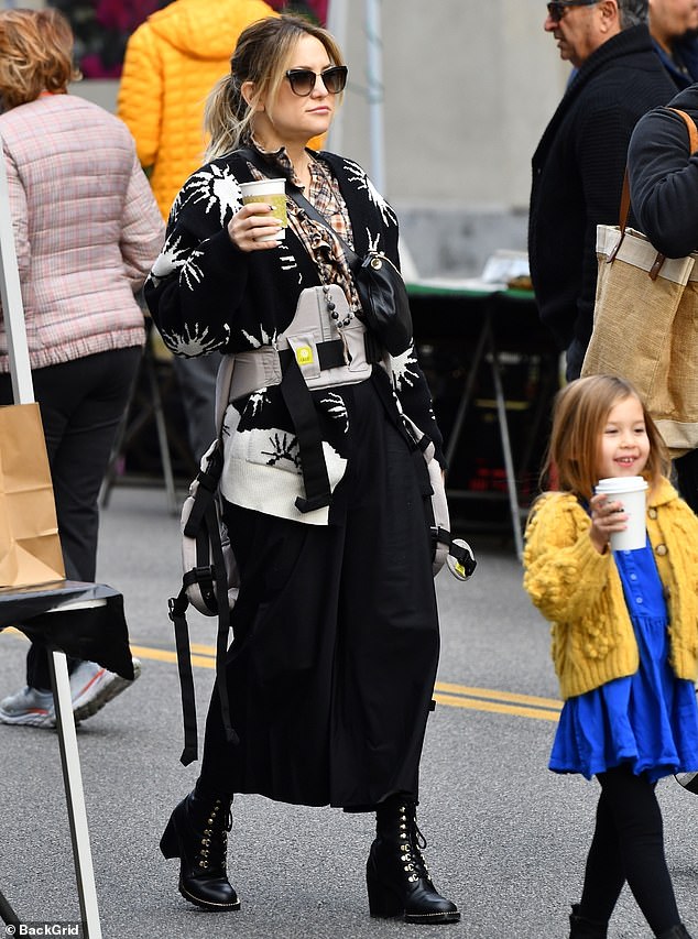 Boho chic: Kate looked cozy and chic in a flannel shirt and black cardigan embroidered with white suns  She donned a black midi skirt and lace-up black combat boots, giving it a punk edge.