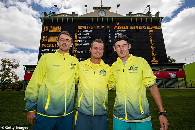 Australian team members Millman, Lleyton Hewitt and de Minaur pose in front of the old scoreboard at Adelaide Oval ahead of a Davis Cup qualifying tie