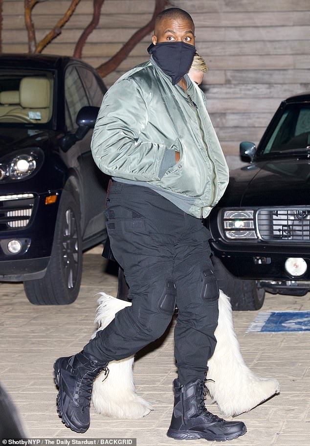 Dad look: Kanye rocked an army green puffer jacket, black cargo pants and boots  On his pants were pads on his knees.