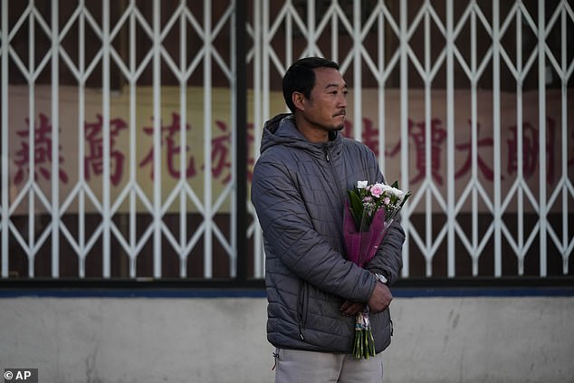Hunter Zhao, 41, holds flowers in honor of the victims killed in the Saturday ballroom studio shooting in Monterey Park, Calif., Sunday, January 22, 2023.