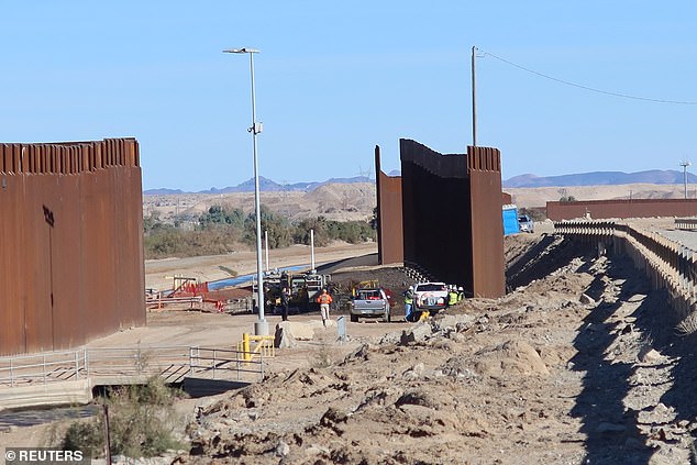 Construction workers stand at a job site at the US-Mexico border where work has begun to fill the border gaps, previously filled by shipping containers, in Yuma, Arizona, US, January 12. of 2023