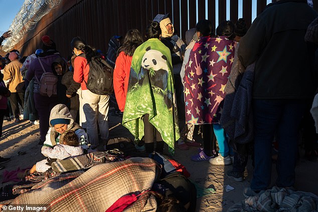 Immigrants line up to report to US Border Patrol agents after spending the night camped out along the US-Mexico border fence on December 22, 2022.