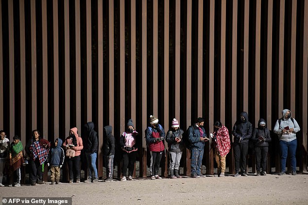 Asylum seekers line up to be processed by US Customs and Border Patrol agents at a gap in the US-Mexico border fence near Somerton, Arizona on December 26, 2022.