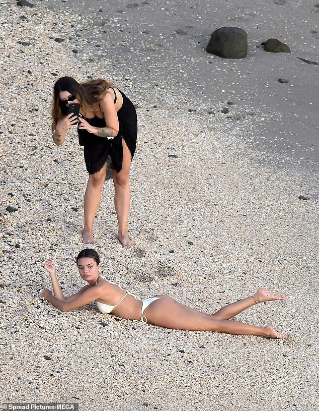 A woman in a black dress offered to take photos of Sophia lying on the stony sand