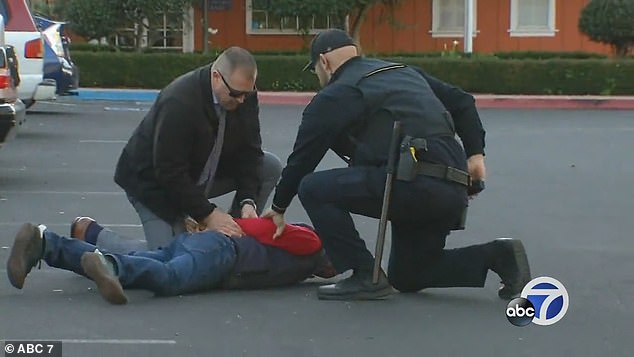 Zhao is seen being restrained and searched, before being handcuffed and put in the police car.