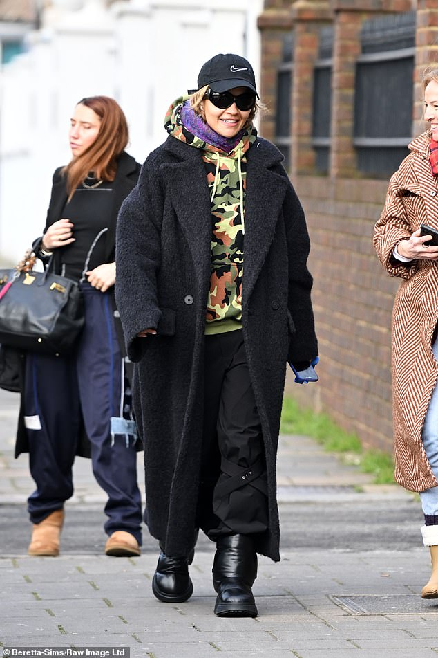 Staying warm: Rita opted for a pair of black utility pants for the outing, teamed with a camo hoodie and a warm purple hairnet.