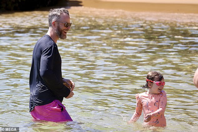 Hamish, 41, dressed in a black waterproof vest and pink swim trunks.