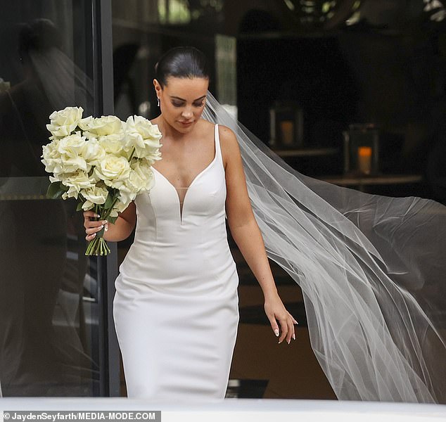 She grabbed a bouquet of cream roses that matched her French-tip manicure.