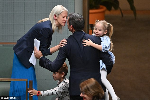 Four of the bracelets have cultural significance, while one is a gift from Chalmer's daughter Annabel, above in his arms in Parliament with his wife Laura (left) after he delivered his first budget last October.