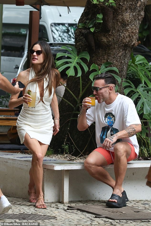 Refreshment: The runway star was seen having a refreshing drink while laughing with her friend Matheus Mazzafera, as they waited for a table at a popular restaurant in Rio de Janeiro