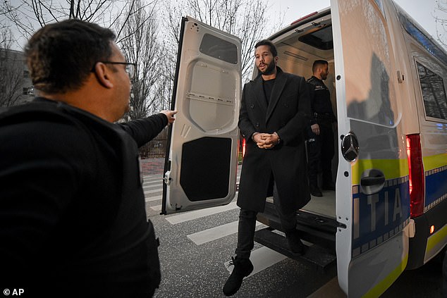 Police officers escort Tristan Tate outside the Directorate for Investigating Organized Crime and Terrorism (DIICOT) where prosecutors examine electronic equipment confiscated during the investigation in their case in Bucharest on Wednesday