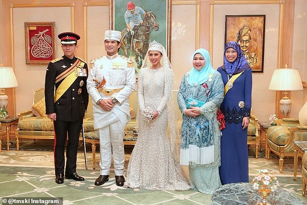 The newlyweds pose with guests after their first wedding.  The bride dazzled in a sparkling white dress with a mermaid skirt and matching veil.