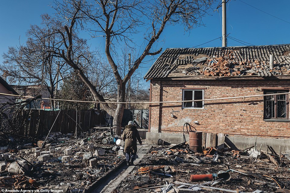 A woman walks past a damaged house in Bakhmut, a city that has been the focus of fierce fighting.