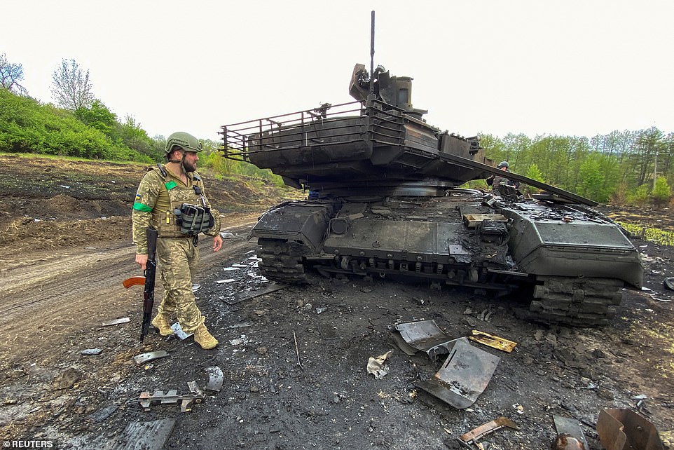 Pictured: A Ukrainian serviceman walks next to a destroyed Russian main battle tank T-90M Proryv, in Staryi Saltiv in the Kharkiv region on May 9