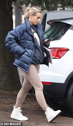 Out and about: The reality star opted for a pair of crisp, chunky white sneakers as she made her way to her car while checking her phone